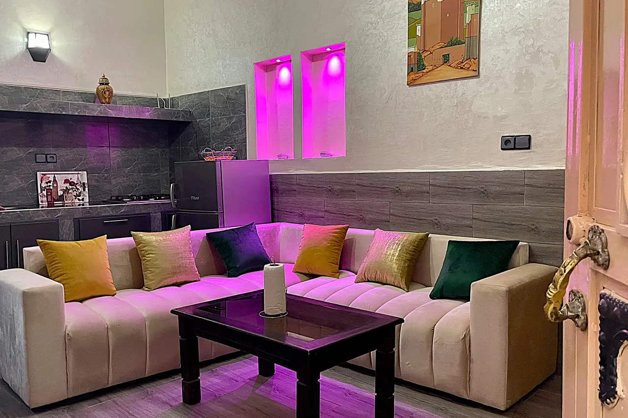 Modern living room with sectional sofa, colorful cushions and pink LED accent niches