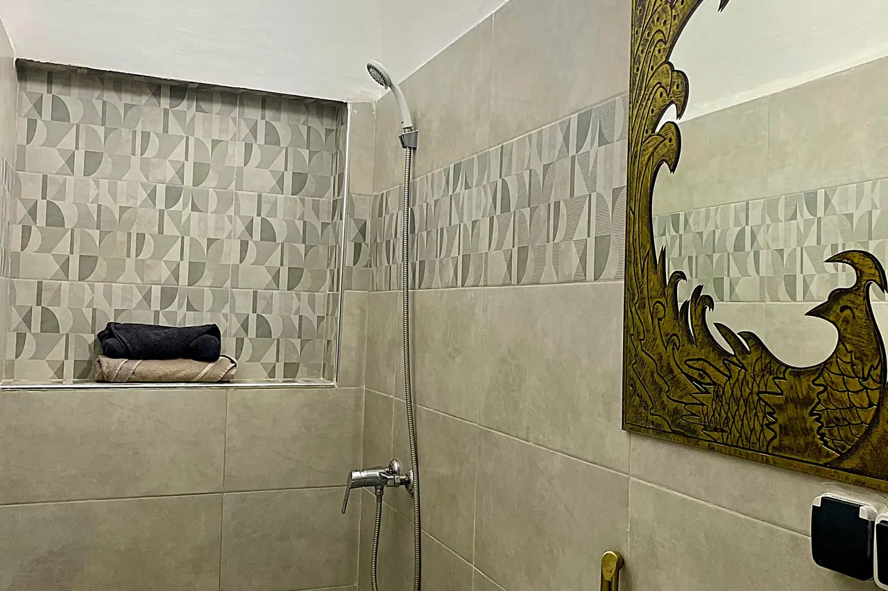 Modern bathroom with walk-in shower and ornate gold Moroccan-style mirror