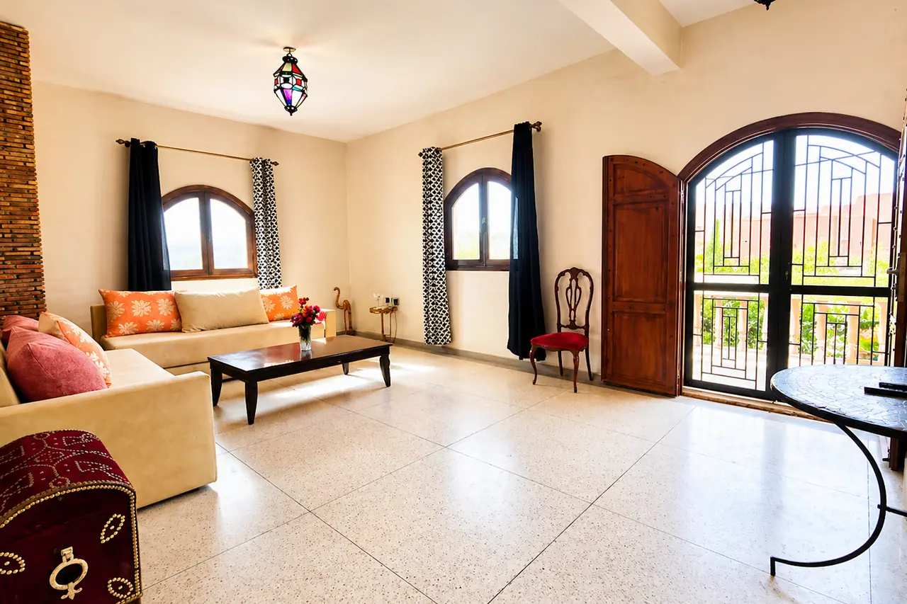 Salon principal lumineux avec colonne en briques, fenêtres cintrées et lanterne marocaine