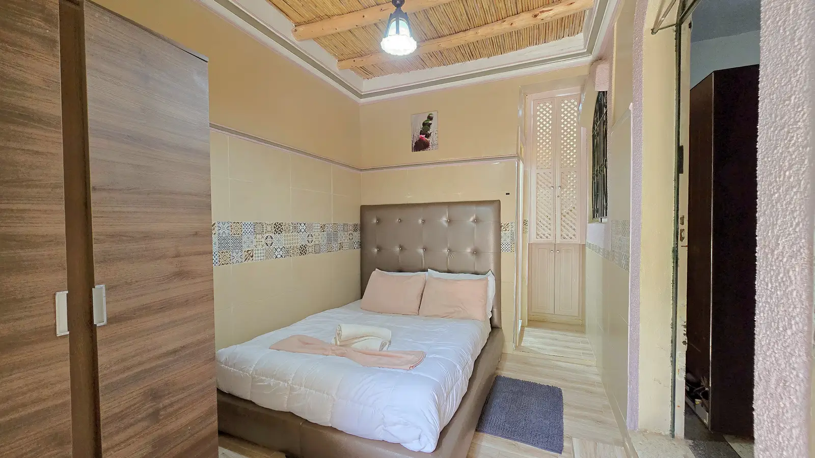 Bedroom — double bed with padded headboard, traditional reed ceiling and patterned tile frieze