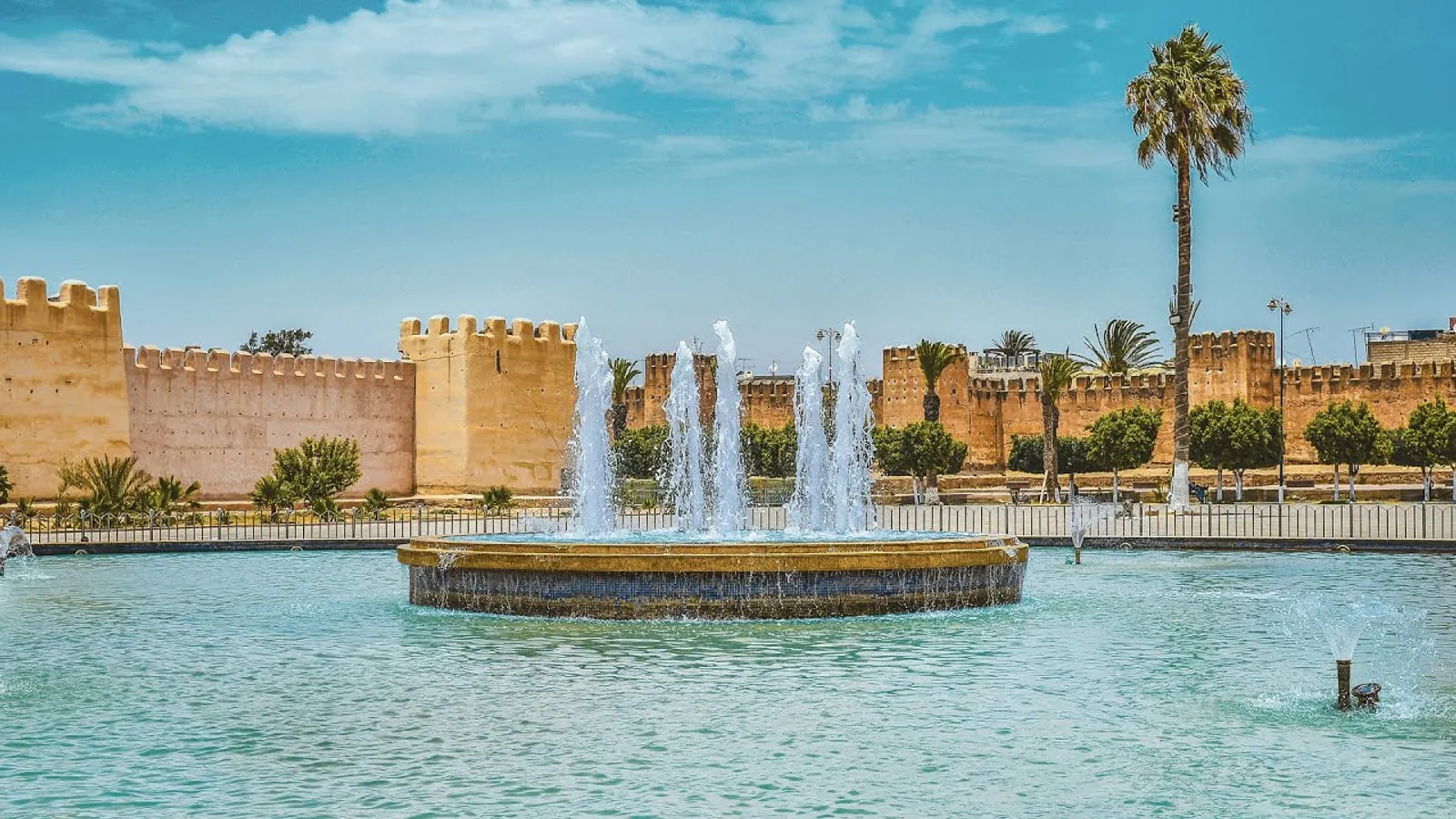 Taroudant ramparts and Place al-Alaouine fountain under a bright blue sky